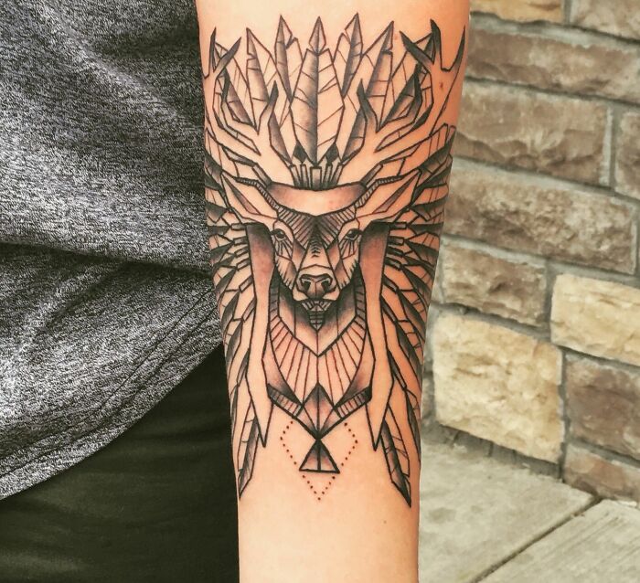 Geometric tattoo of a stylized deer with intricate lines on a person's forearm.