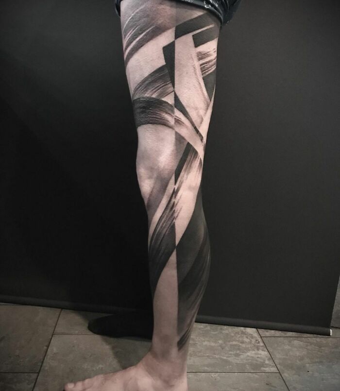 Leg with intricate geometric tattoo, featuring bold black patterns, showcasing creativity and artistic design.