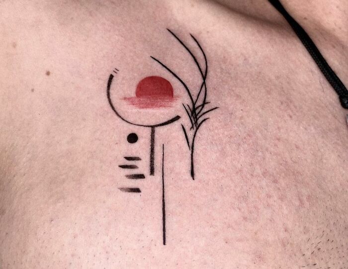 Minimalist geometric tattoo with red circle and black lines on skin, showcasing creativity in geometric tattoo design.