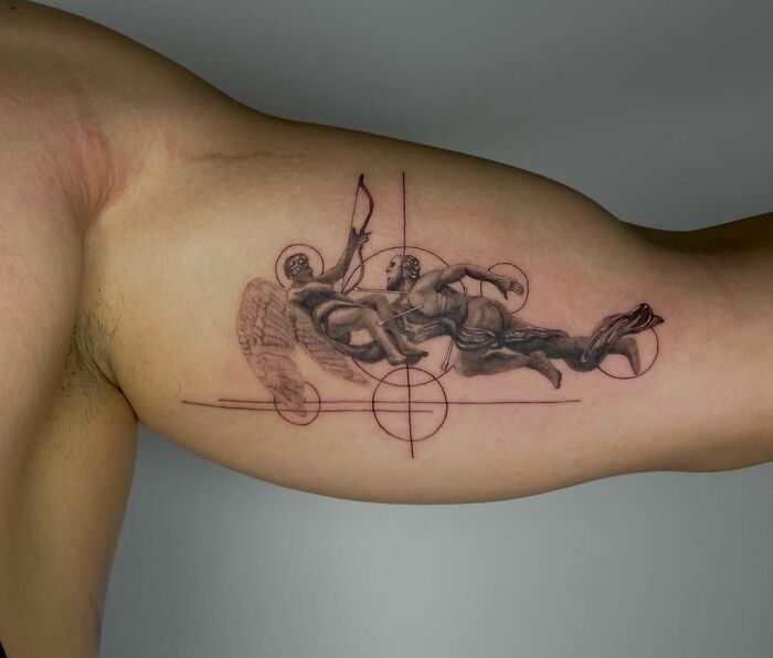 Geometric tattoo on an arm featuring two figures with wings and bow, intersected by lines and circles.