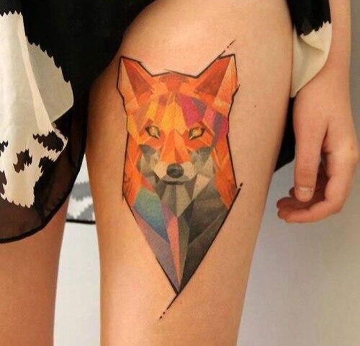 Geometric tattoo of a stylized fox composed of vibrant shapes on a person's thigh, highlighting creativity.