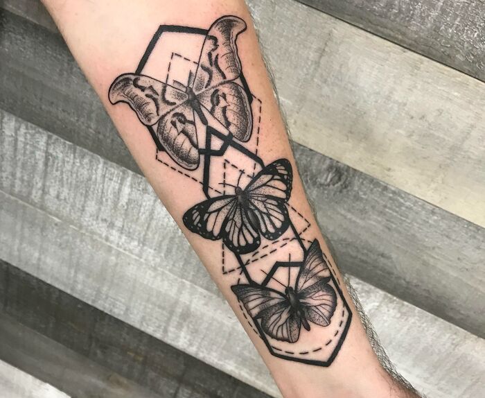 Geometric tattoo featuring butterflies with detailed line work on forearm.
