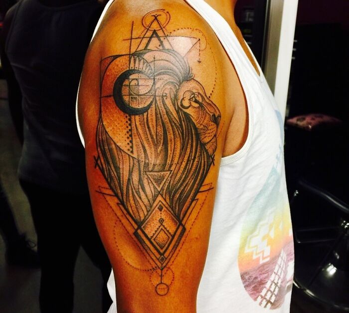 Geometric tattoo of a lion's head with intricate patterns on a person's arm.
