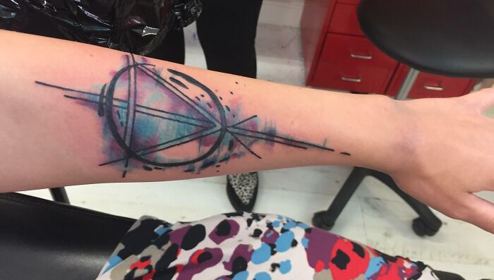 Black and watercolor abstract geometric tattoo on arm