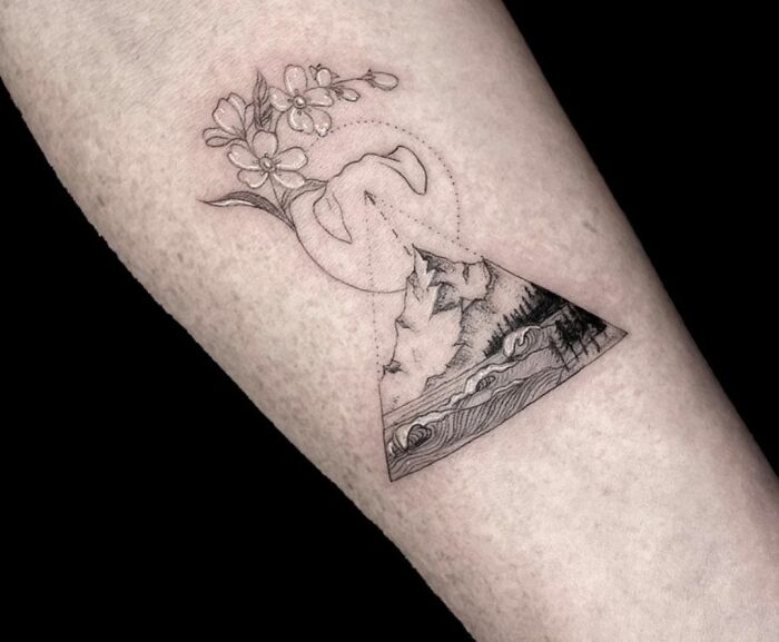Geometric tattoo with mountain, wave, and flower elements on an arm, showcasing creativity in shapes and forms.