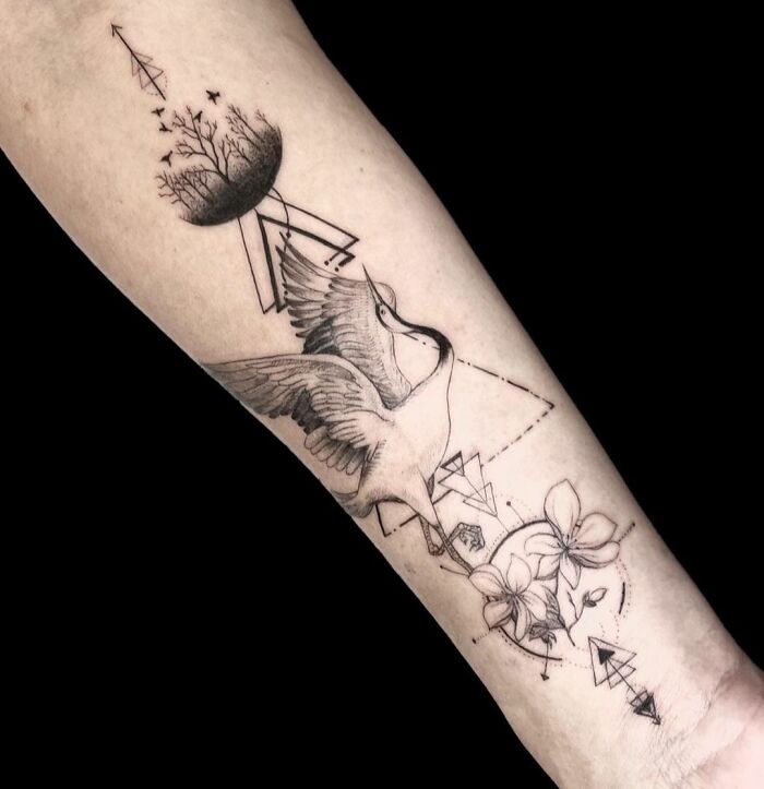 Geometric tattoo with a crane, trees, and flowers on the forearm, showcasing creativity in design.