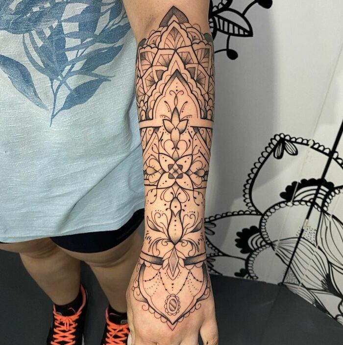 Geometric tattoo design covering forearm, showcasing intricate shapes, forms, and creativity in black ink.