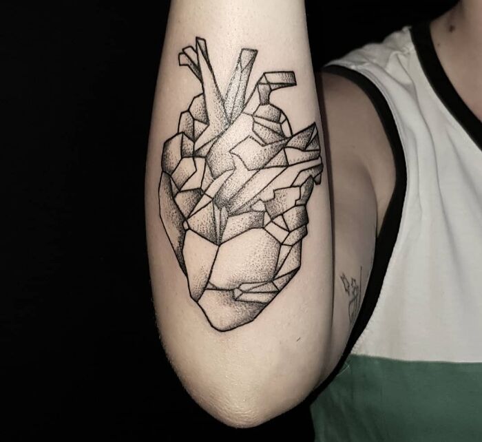 Geometric tattoo of a heart on forearm, showcasing creativity with intricate linework and shading.