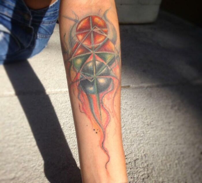 Geometric tattoo on forearm, featuring colorful intersecting shapes and intricate forms.