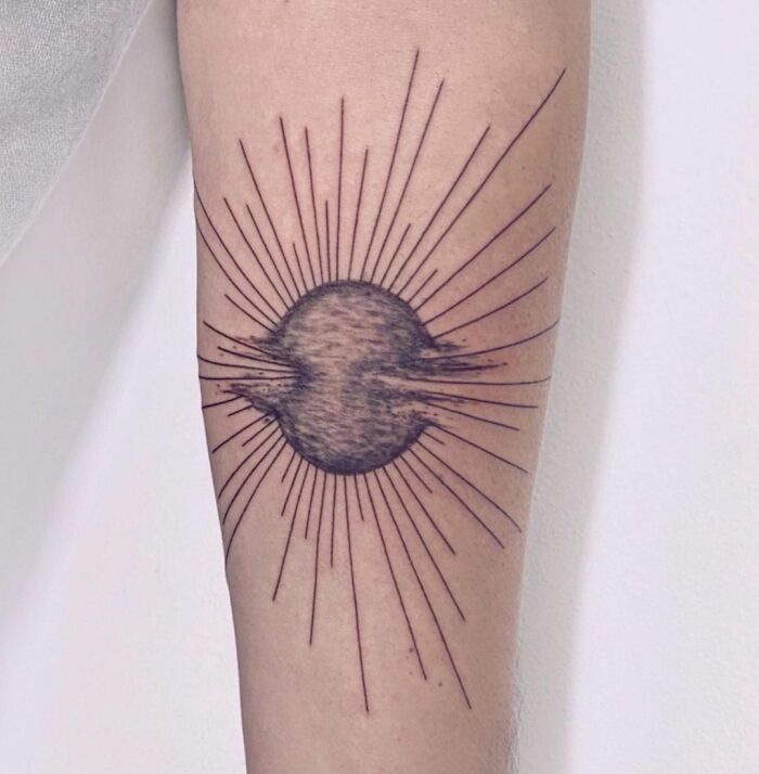 Geometric tattoo on forearm featuring a circular center with radiating lines, exemplifying creative design.