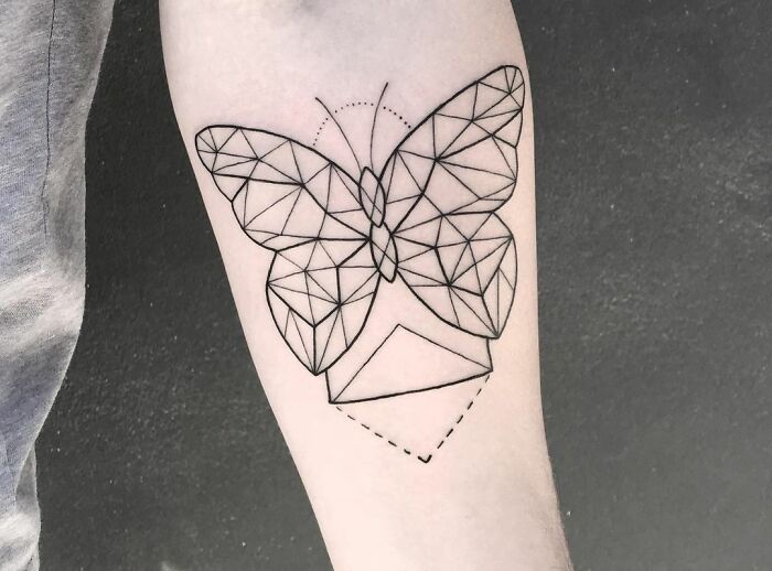Geometric butterfly tattoo with intricate lines on forearm.