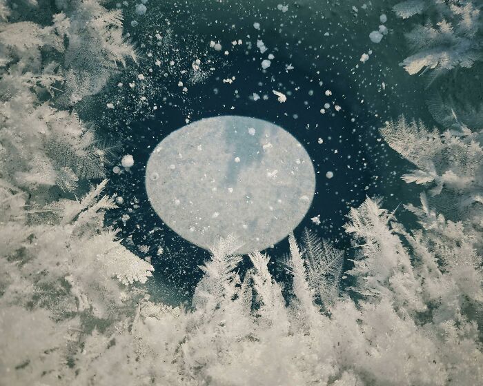 This Bubble In A Frozen-Over Ice Fishing Hole Looks Like The Moon Rising Over A Forest
