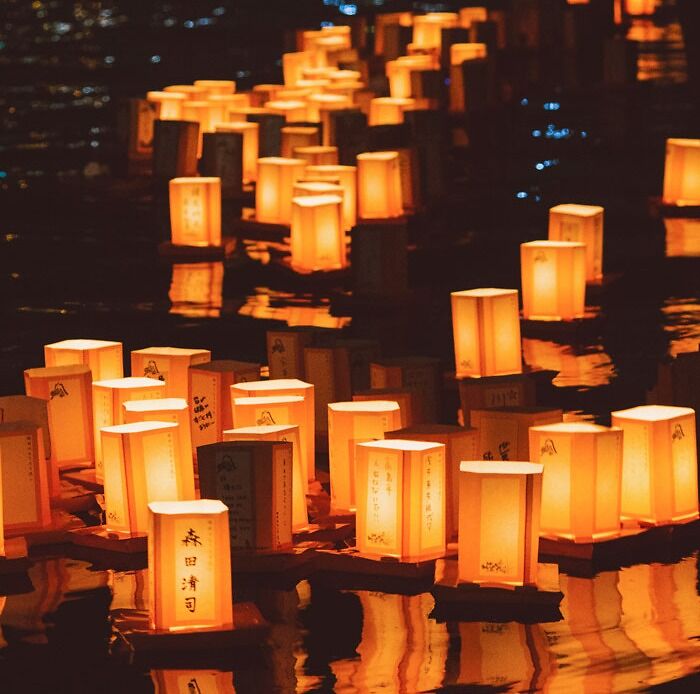 Many lighted lanterns on a water at a night-time