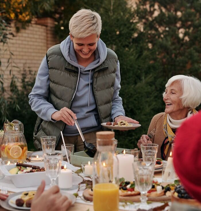 A smiling woman in gray jacket placing food on the table