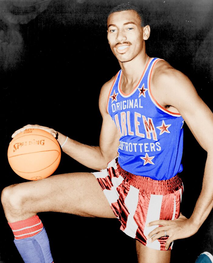 Wilt Chamberlain in Harlem Globetrotters uniform holding basketball, featured in celebrities who never married yet found love.