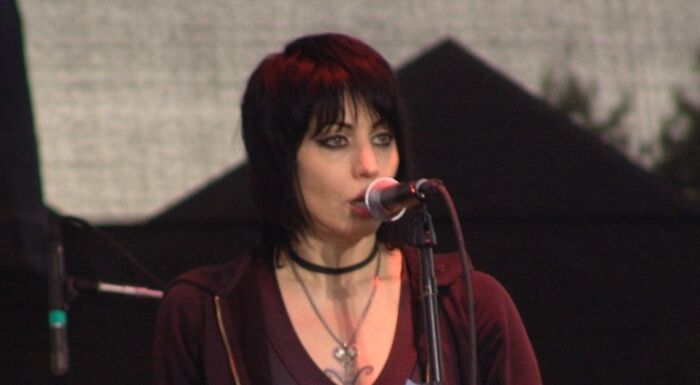Joan Jett speaking into a microphone on stage, representing celebrities who never married yet still found love.