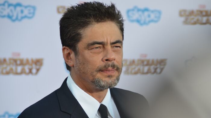 Benicio Del Toro wearing black suit 