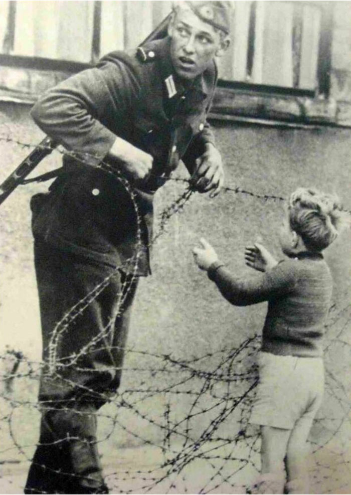 1961. Un soldado de Alemania Oriental ignora las órdenes de no dejar pasar a nadie y ayuda a un niño a cruzar el recién construido Muro de Berlín para reunirse con su familia