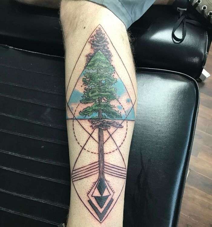 Geometric tattoo with a tree and intricate shapes on a leg.