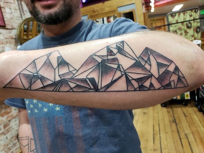Geometric tattoo design on forearm featuring abstract shapes and forms.