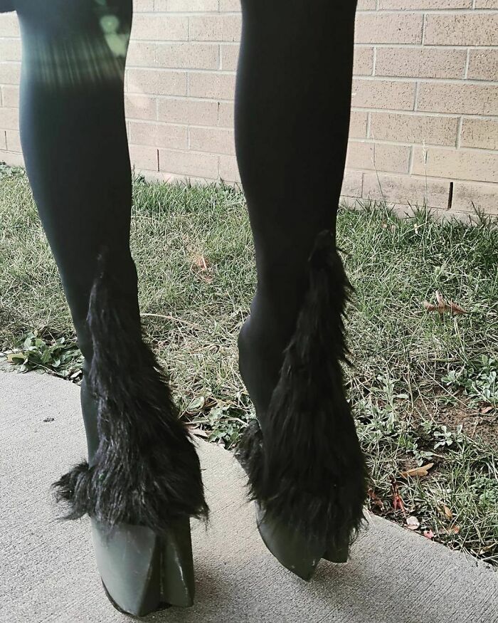 A pair of weird shoes with furry design and hoof-like heels on a sidewalk.