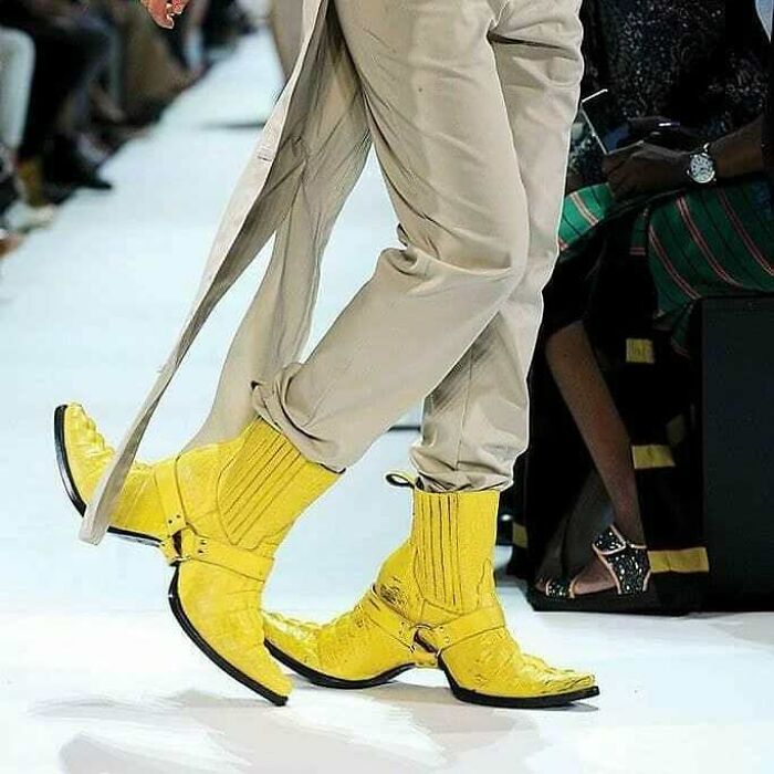 Yellow weird shoes with extended pointed toes on a fashion runway.