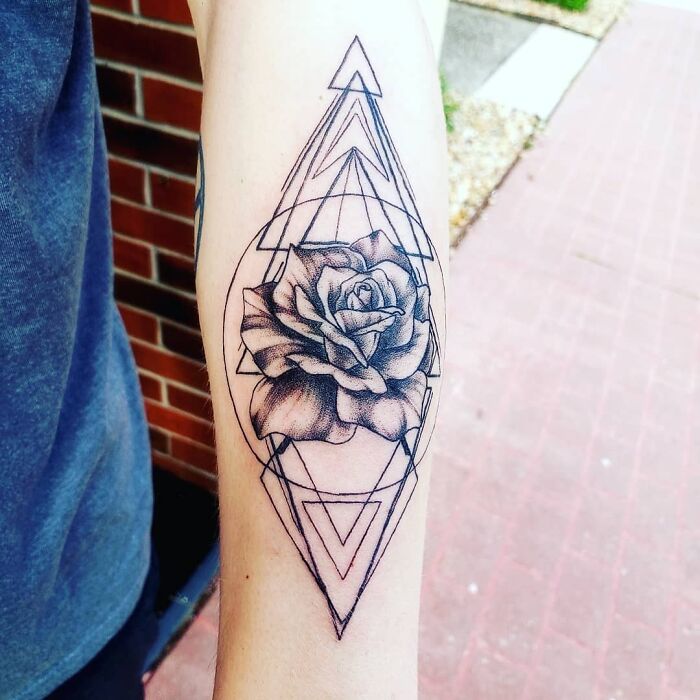 Geometric tattoo design featuring a rose and intricate shapes on an arm.