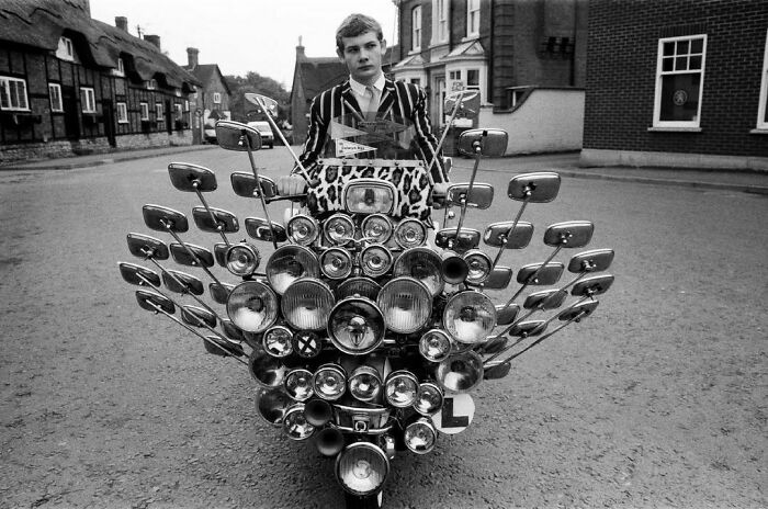 Original Caption: “School Leaver Bryn Owen Aged 17 With His Vespa Scooter, Which Has 34 Mirrors And 81 Lights, All Bought With His Pocket Money. Market Bosworth, Leicestershire, 1983.”