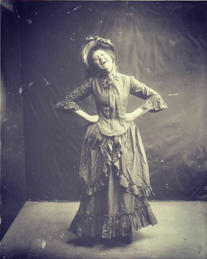 Mujer victoriana desconocida posando de forma inusual para la época y riéndose un poco