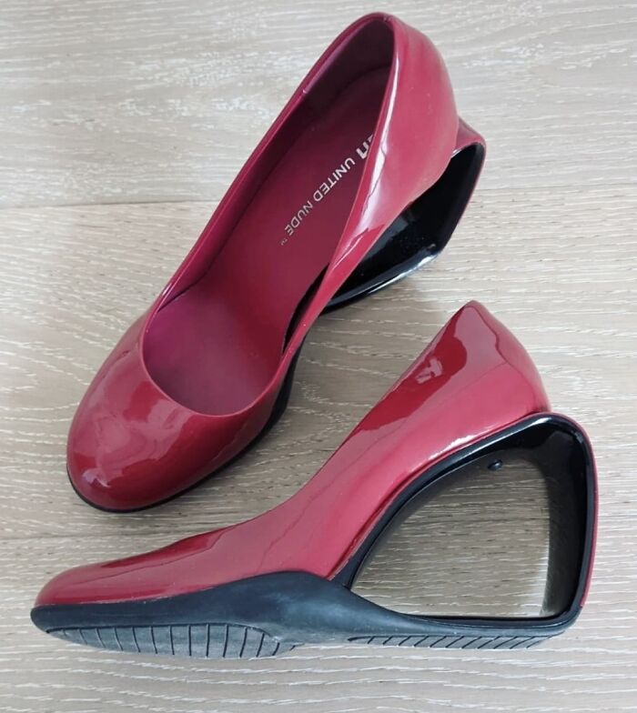 Red weird shoes with a unique open heel design on a wooden floor.