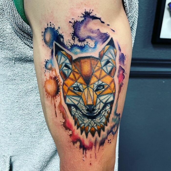 Geometric tattoo design of a fox with colorful shapes and forms on an arm, showcasing creativity.