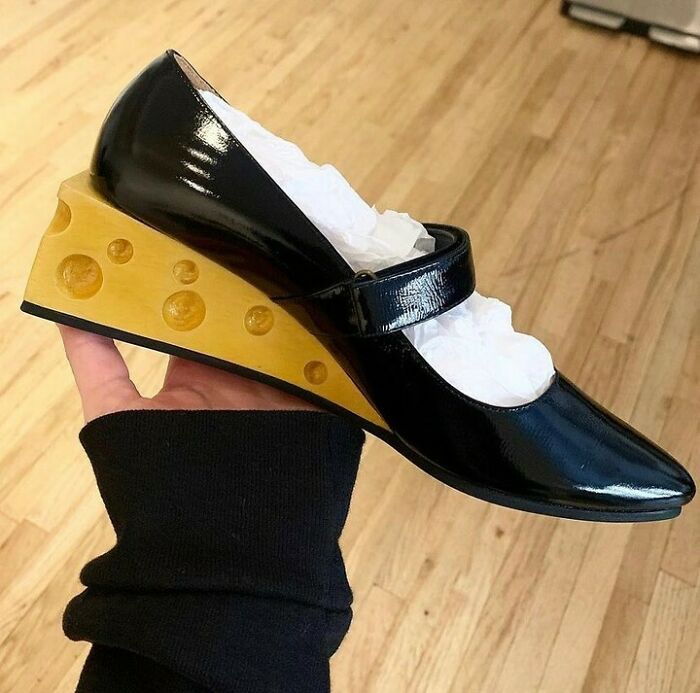 Unusual shoe with a cheese wedge heel design, held in hand.