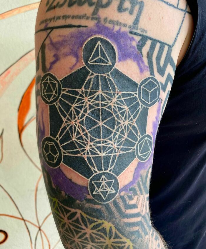 Arm tattoo featuring intricate geometric designs with a vibrant purple background.
