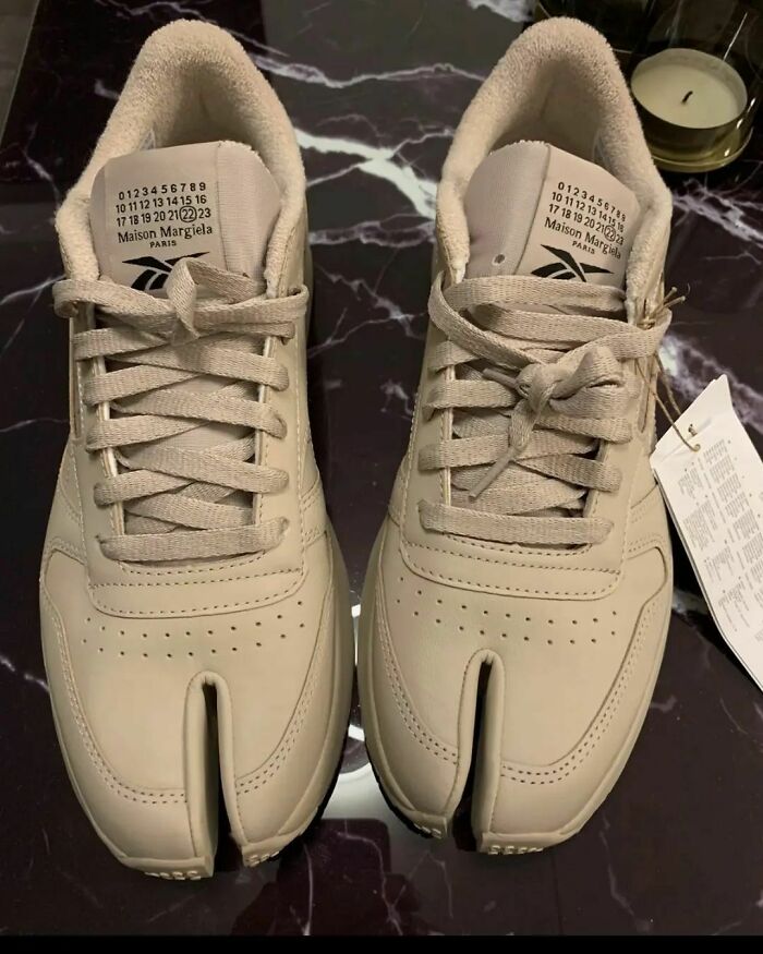 Beige split-toe shoes on a marble surface, featuring unique design elements, exemplifying weird shoe styles.