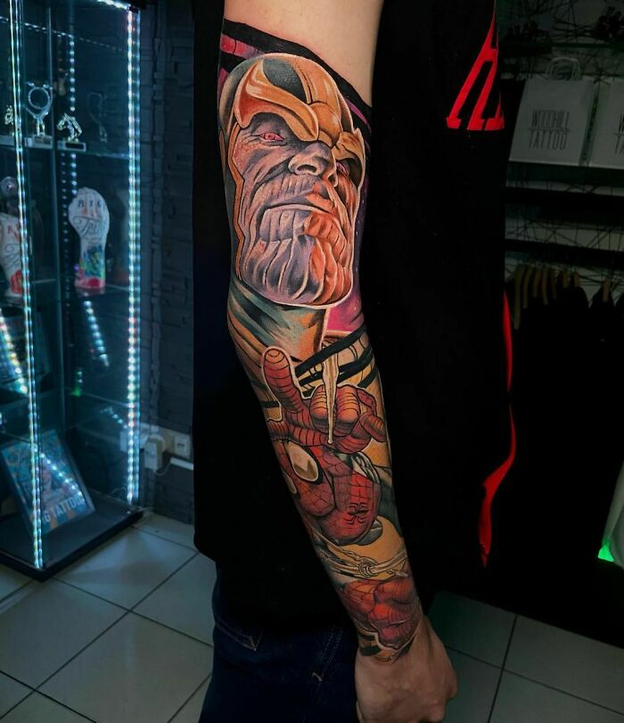 Marvel tattoo sleeve featuring Thanos and Spider-Man art on an arm in a tattoo studio setting.