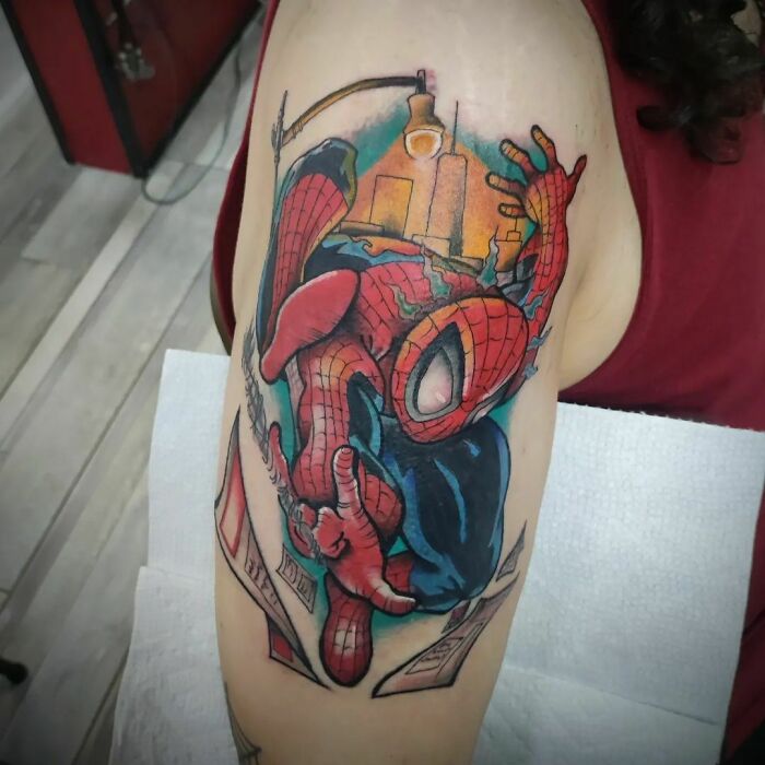 Marvel tattoo featuring Spider-Man with a cityscape background on an upper arm.