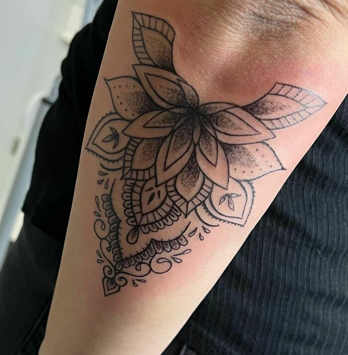 Geometric tattoo with floral elements on a forearm, showcasing intricate artistry and creativity.
