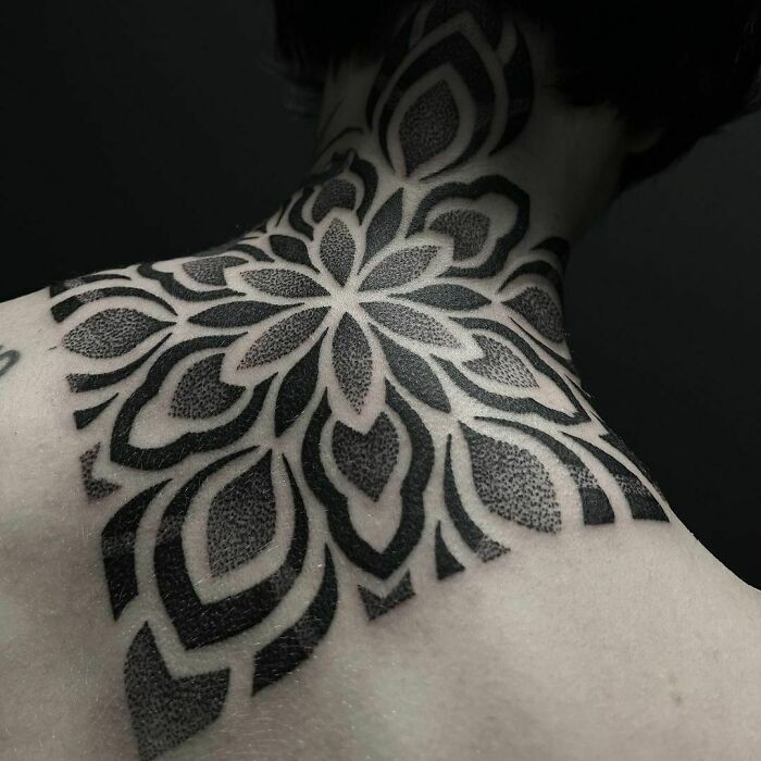 Geometric tattoo design on a person's neck and shoulder, featuring intricate shapes and forms.