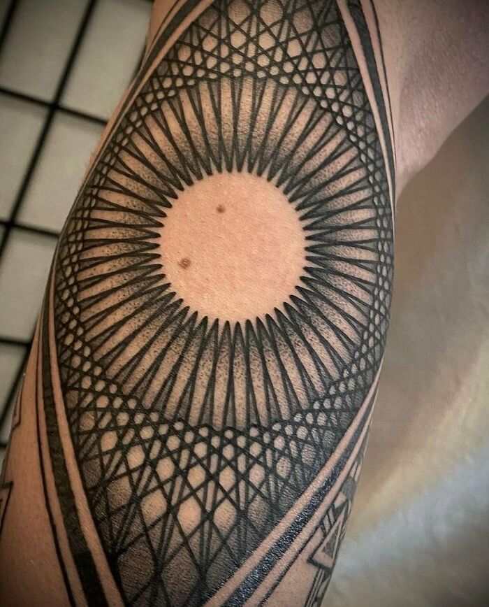 Intricate geometric tattoo design with circular patterns on forearm.