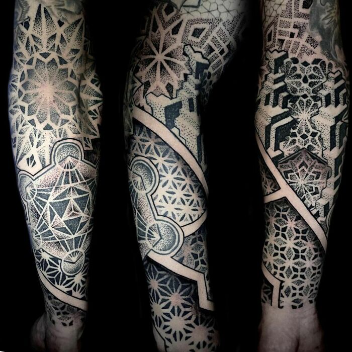 Intricate geometric tattoos covering arms with complex patterns and designs.