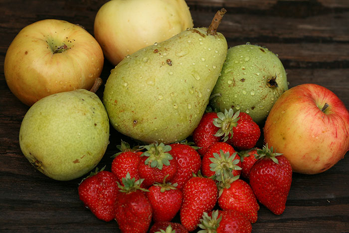 Pears apples and strawberries on a wooden table 