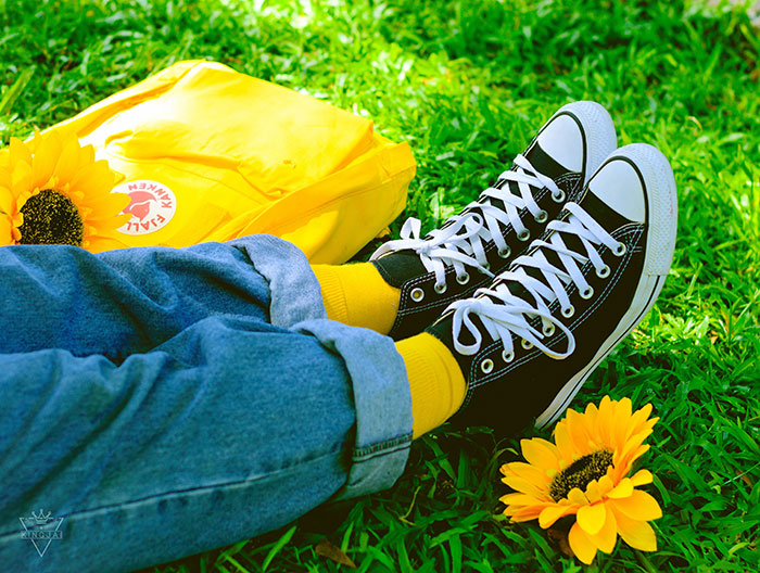 Person wearing converse shoes and laying on grass with yellow colors 