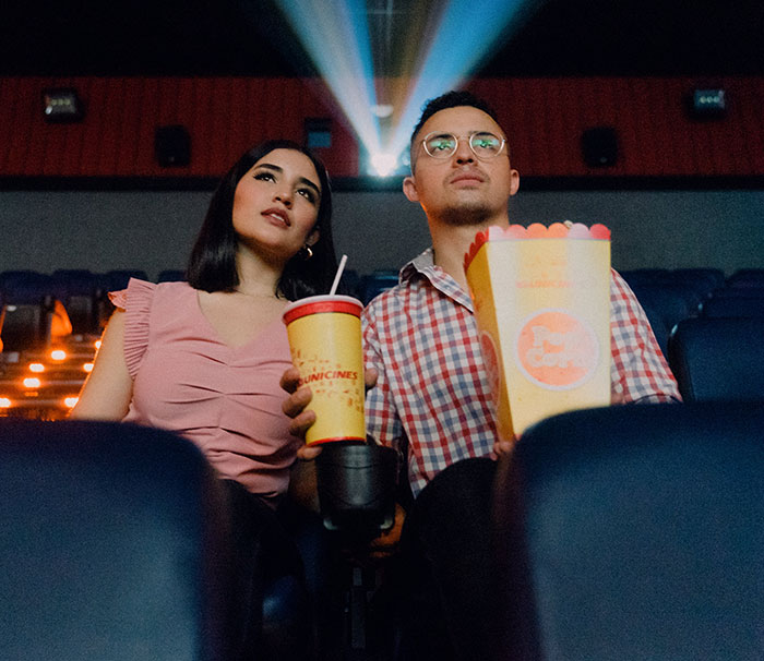 Man and woman holding popcorn and watching a movie in cinema 