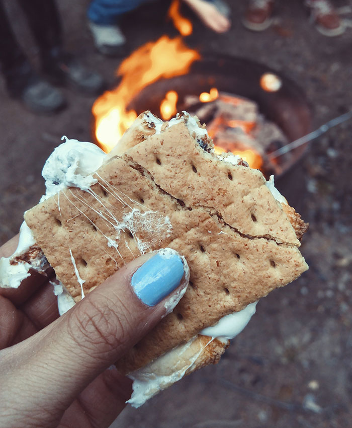 Woman holding s'mores near a campfire 