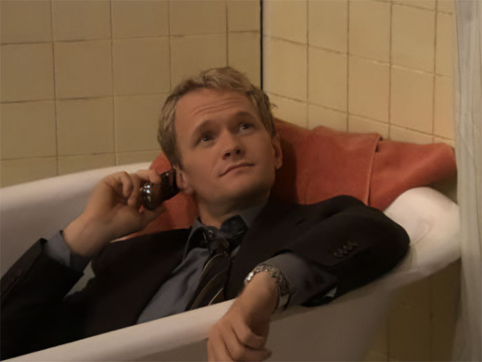 Barnabus Stinson lying in the bath with a suit and talking on the phone