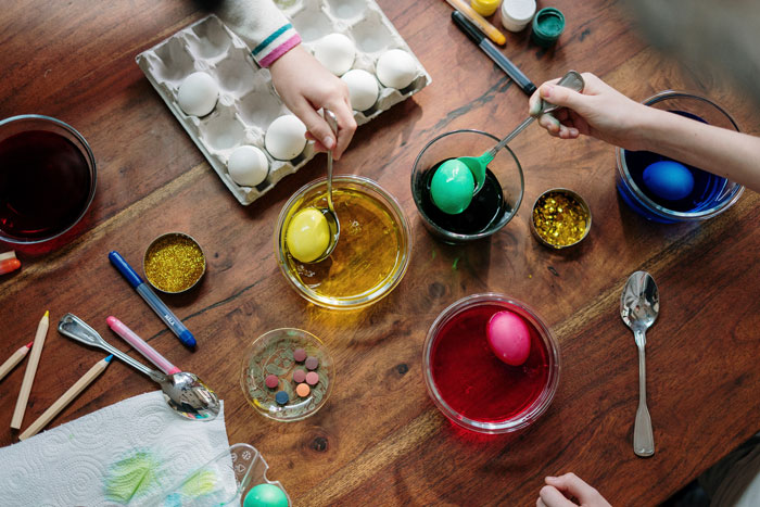 People painting Easter eggs placed on a wooden table