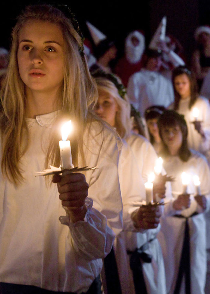 Girls wearing white and holding candles while participating in a Saint Lucy procession in Sweden, 2007