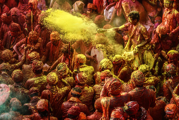 Crowd of people covered in yellow and red paint at Holi festival