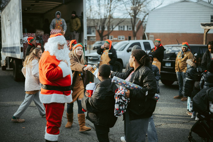 People exchanging gifts with Santa Claus on the street