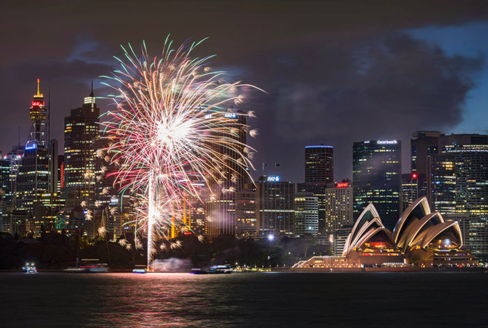 Fireworks display over city buildings and Sydney Opera House during night time